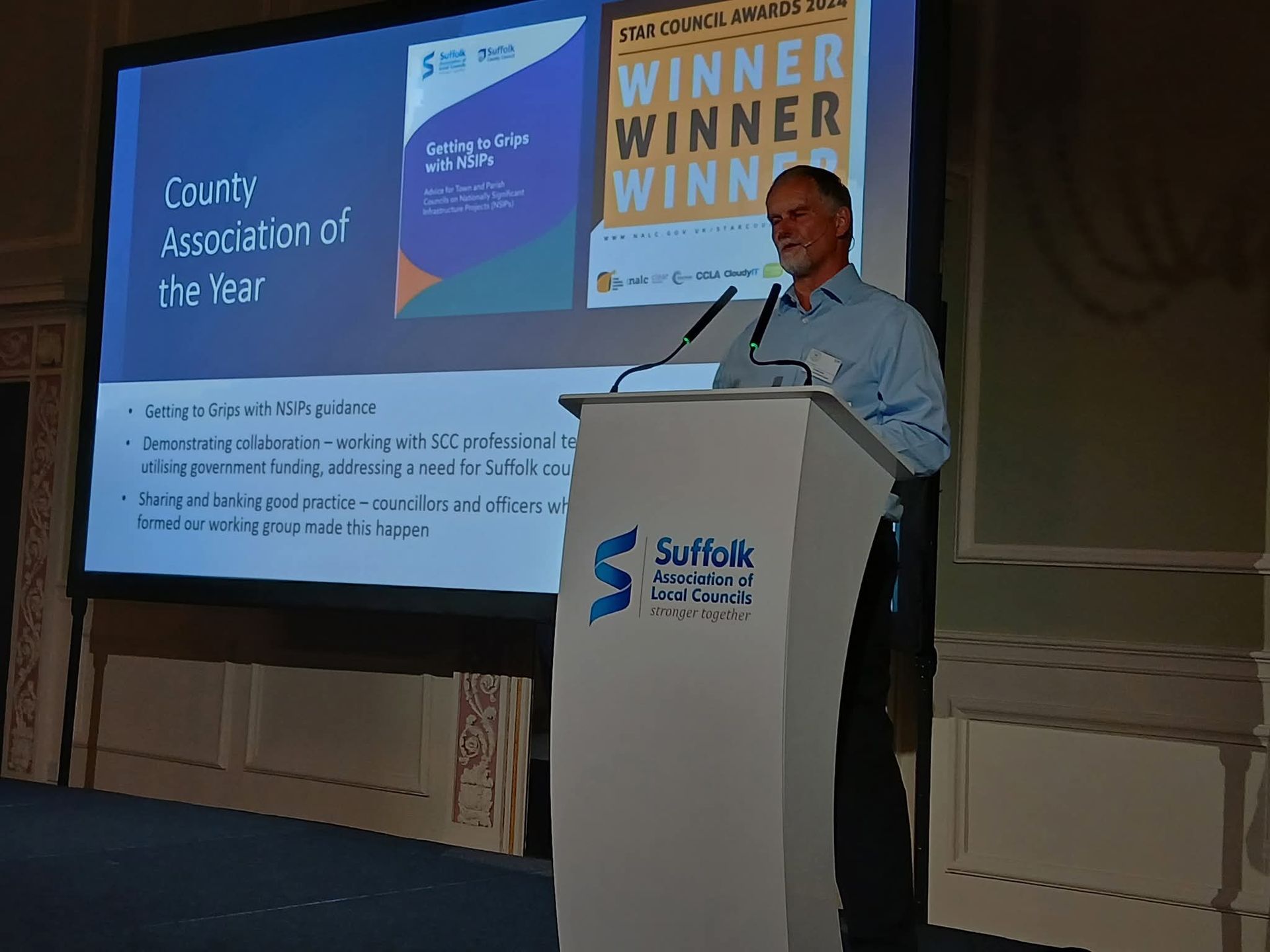 A speaker presents at an awards event, discussing collaboration and guidance for local councils, with a focus on infrastructure projects.